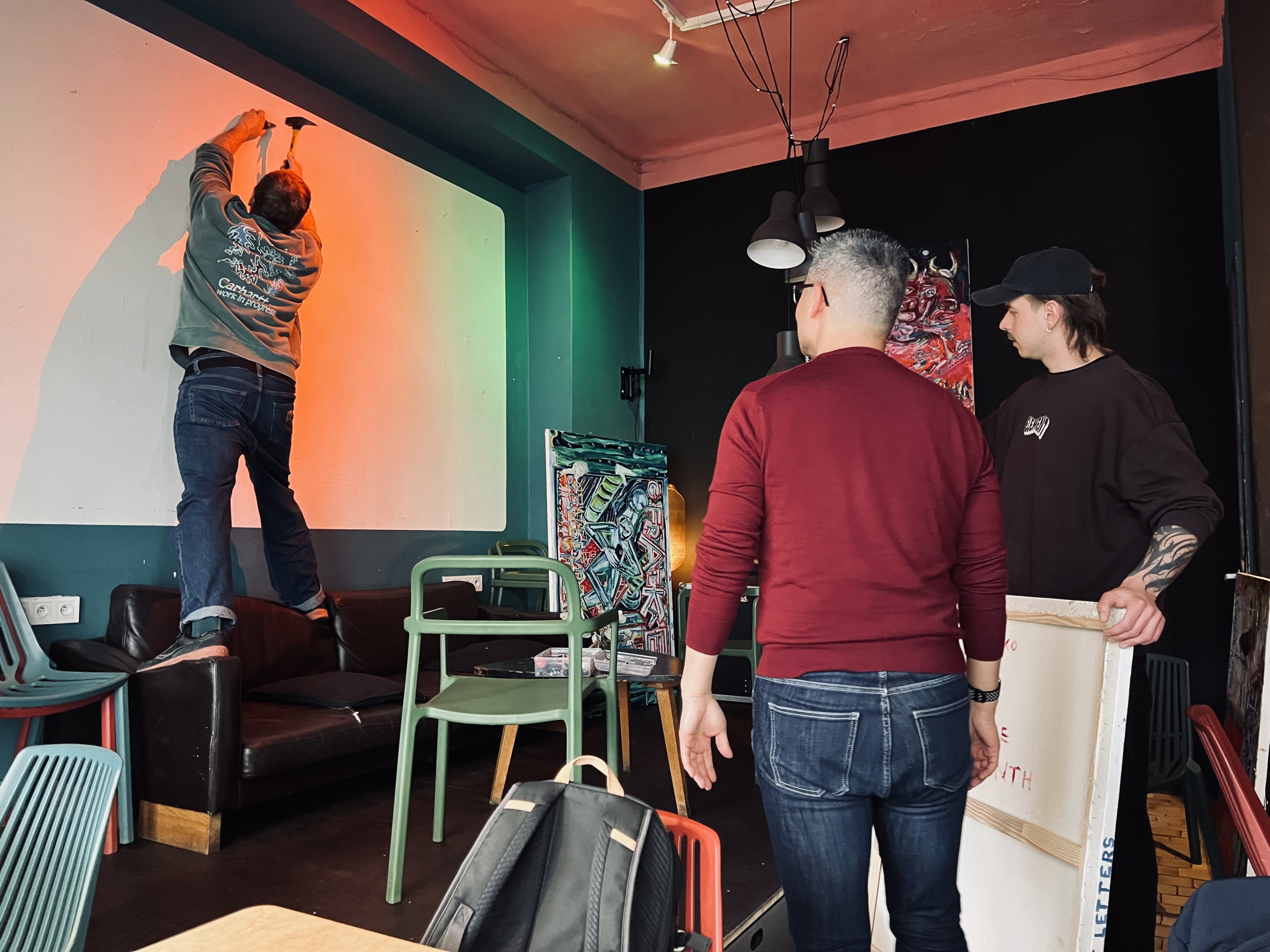 A hanging in progress — a nail into bare plaster, blank canvases waiting.