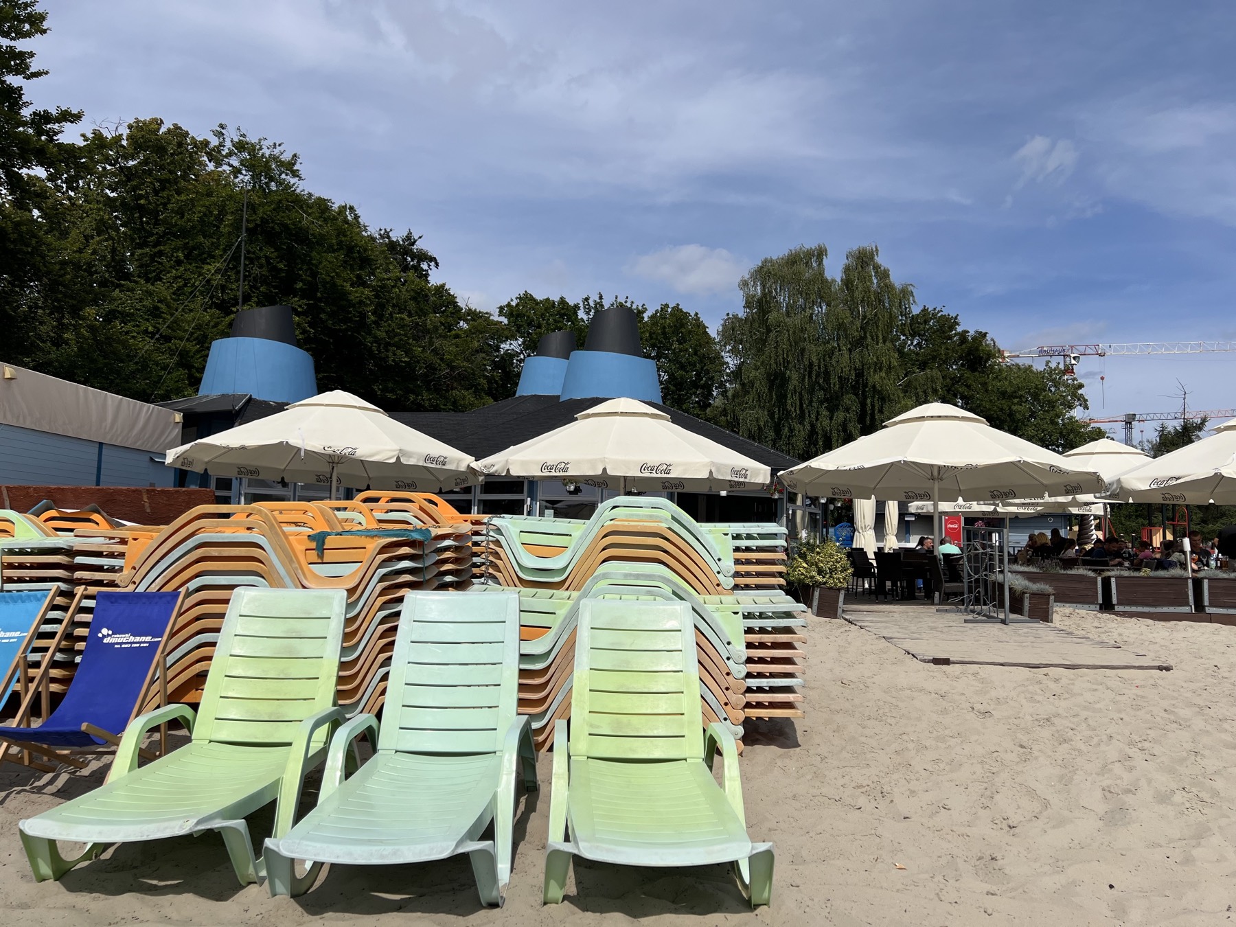 Pastel loungers stacked in a pile at the city beach, with a beach bar built with blue funnels
