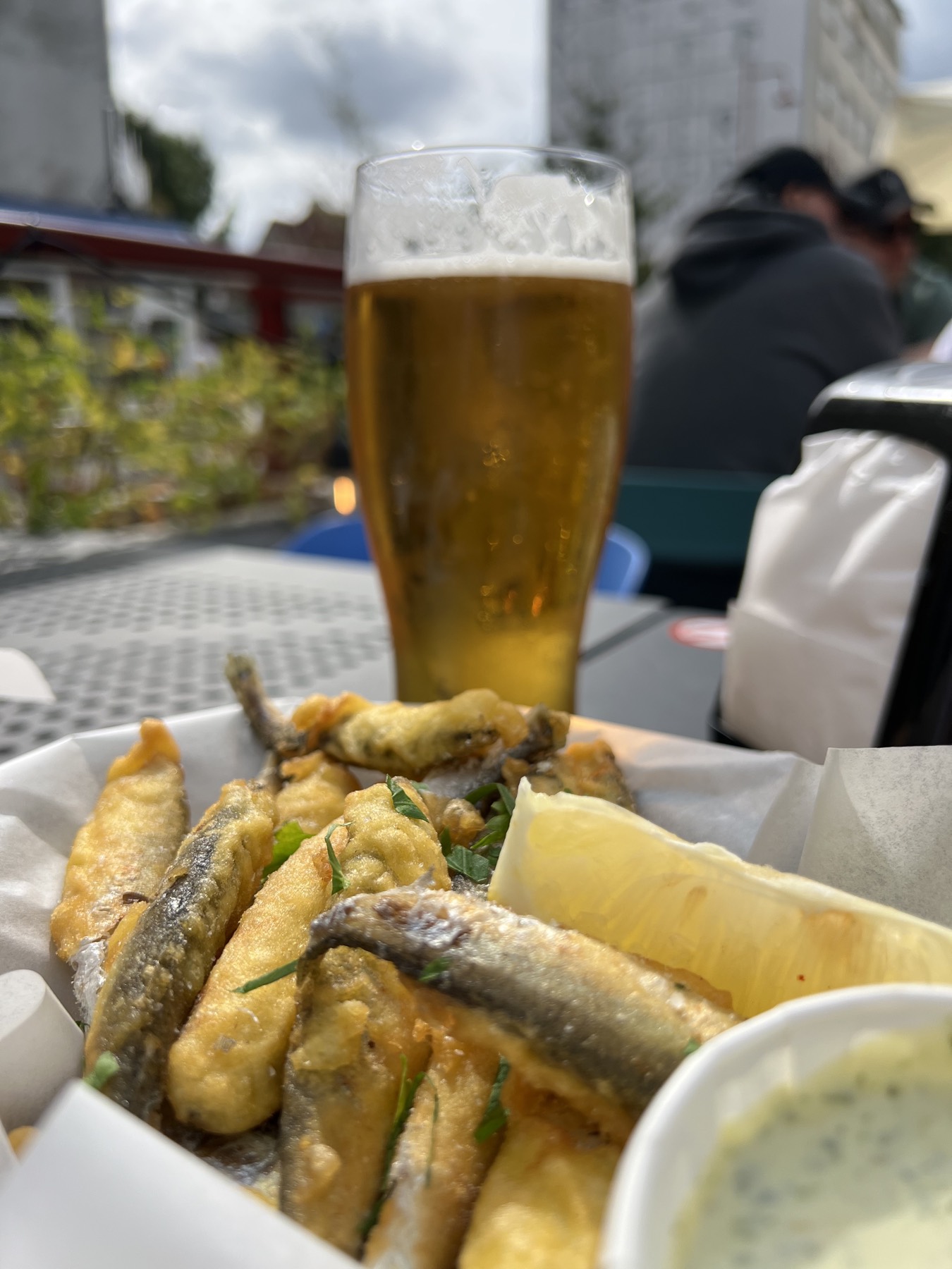 Fried Baltic sprats with a lemon and a lager, sitting outside
